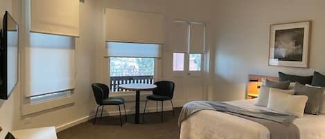 Ein Schlafzimmer mit einem Bett, einem Schreibtisch, zwei Stühlen, einem Deckenventilator und einem Fenster mit Blick.