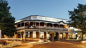 A historic hotel with a balcony and multiple storefronts, including a vintage and an art deco store.