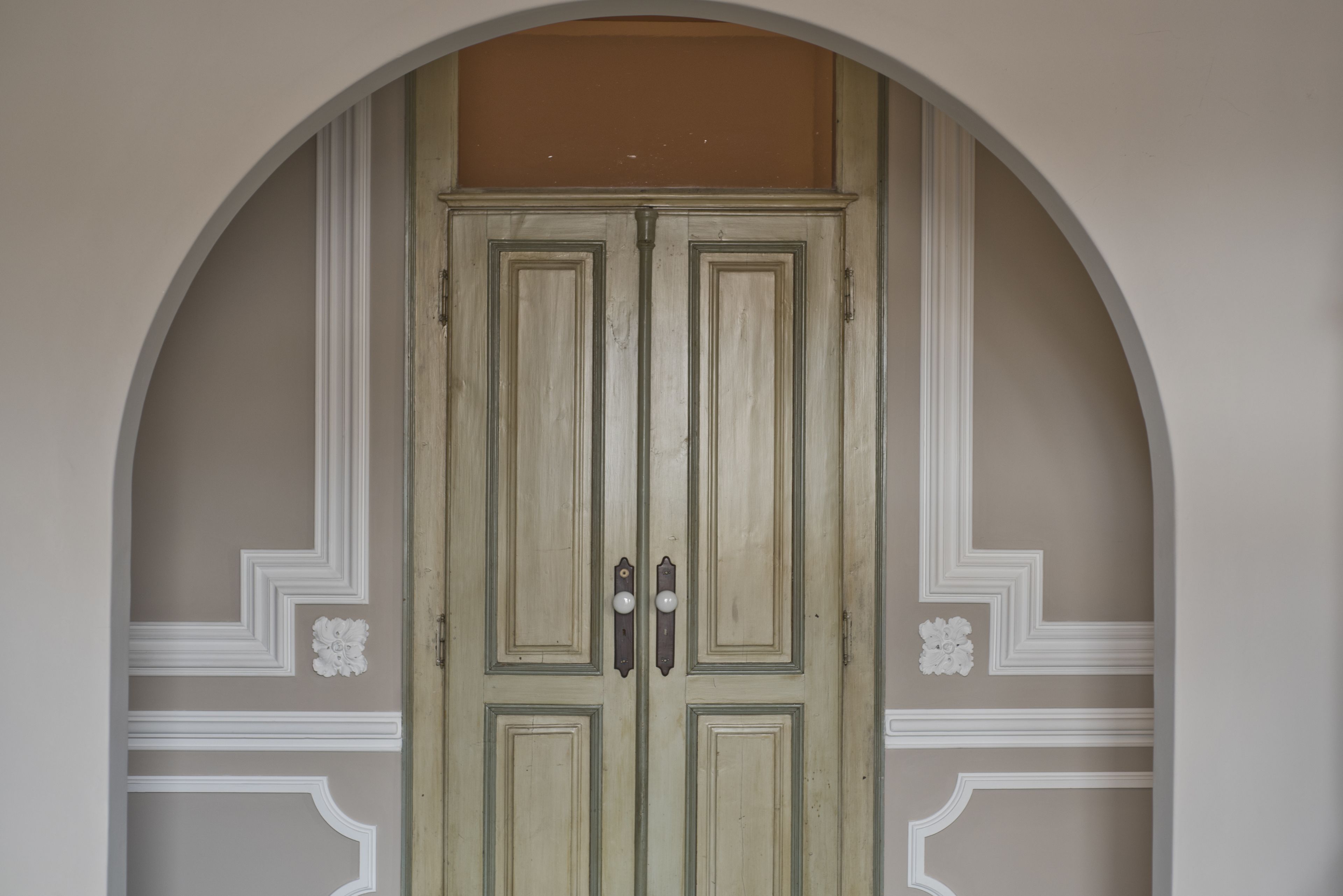 Un portone doppio sormontato da un arco decorativo.