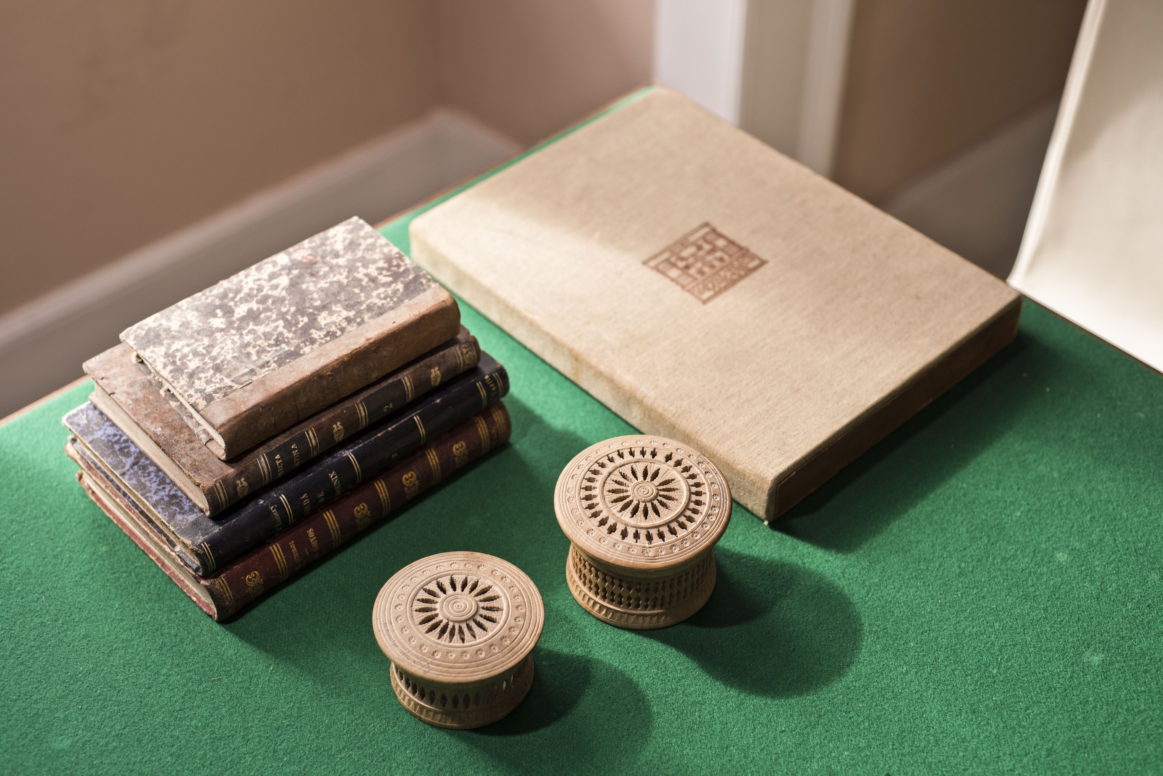 Un montón de libros y dos madejas de madera decorativas sobre una superficie verde.