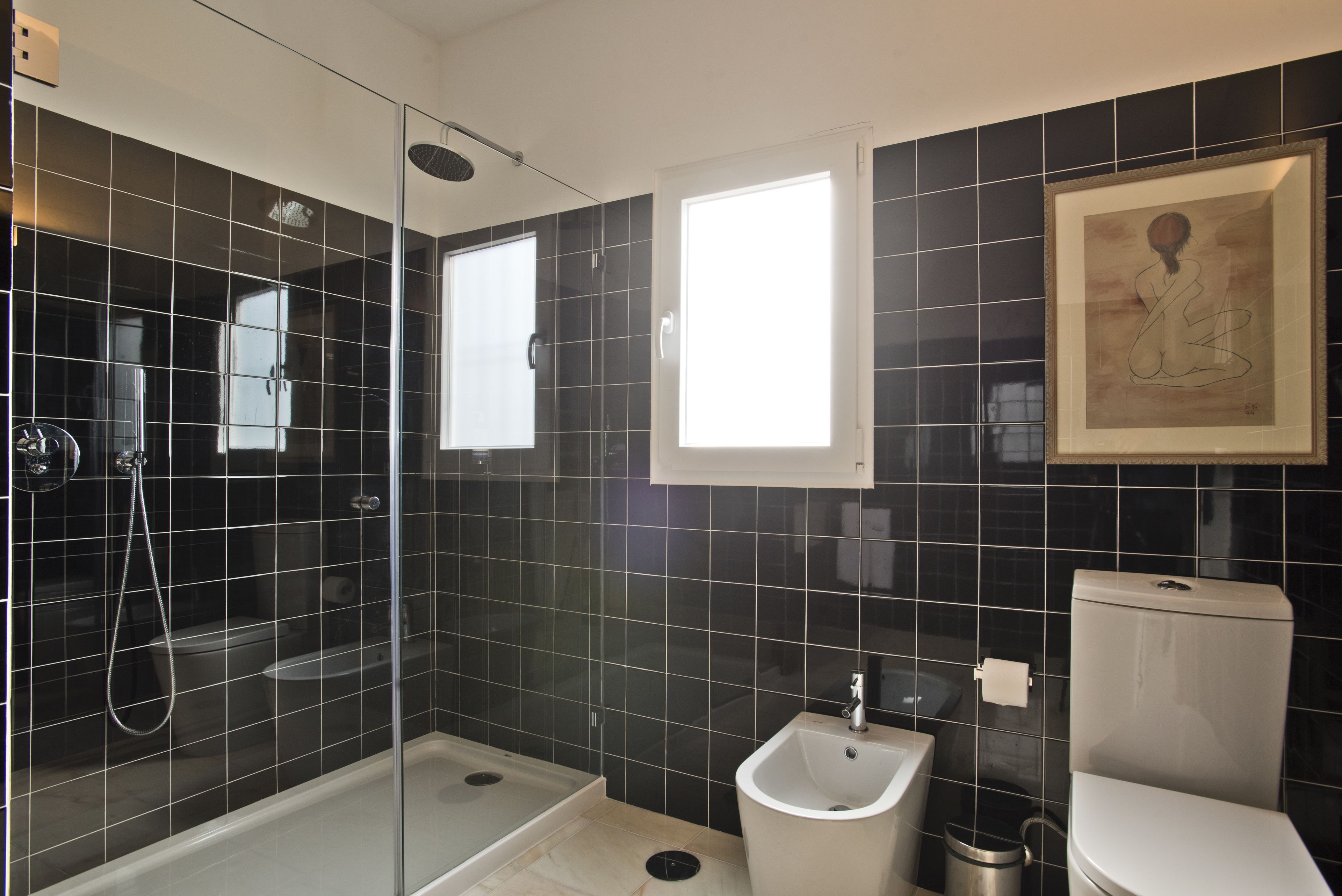 A modern bathroom with a glass-enclosed shower, a bidet, and a toilet.