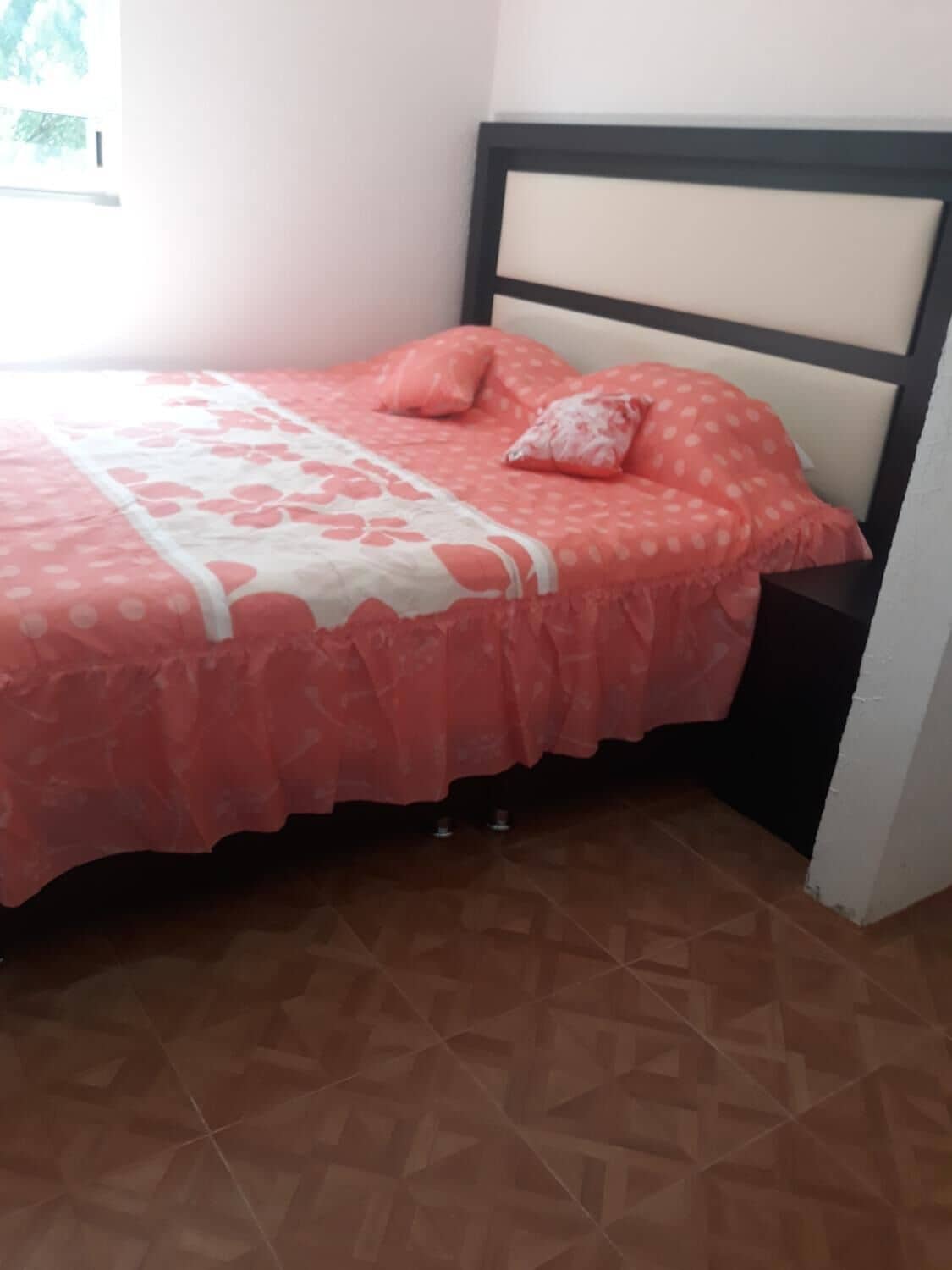 A bed with a patterned bedspread, pillows, and a headboard.