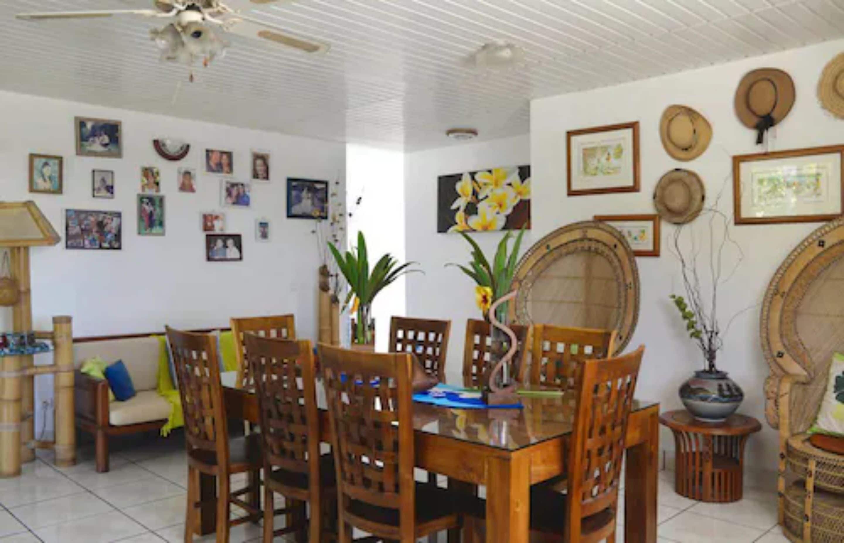 Un comedor con una mesa y sillas de madera, rodeado de cuadros enmarcados y objetos decorativos en las paredes.
