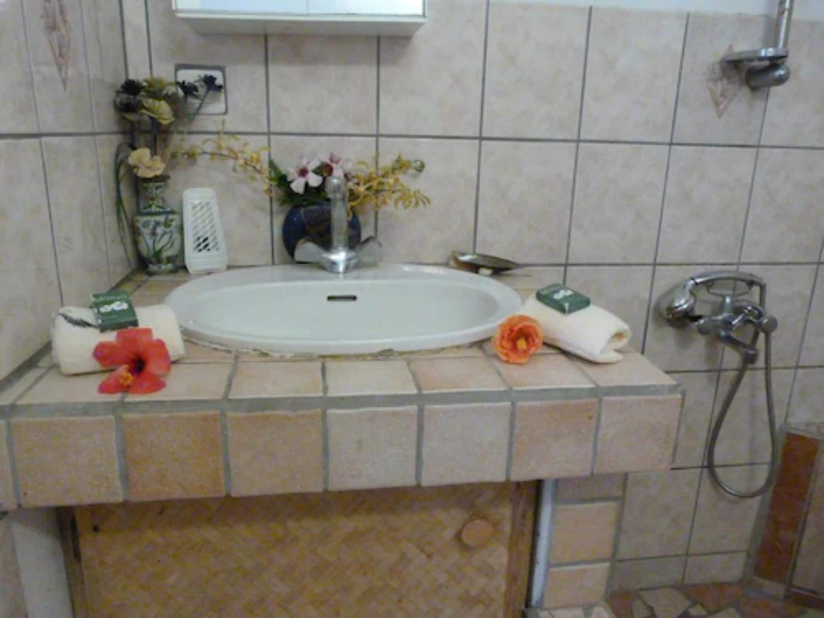 A bathroom with a white sink, a shower, and a towel rack.