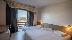 A hotel room with two beds, a desk, and a view of the beach. - Hotel das Figueiras (Sao Lourenco do Sul)