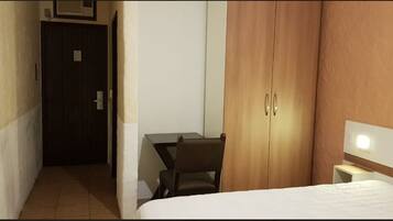 A hotel room with a bed, a desk, and a wardrobe.