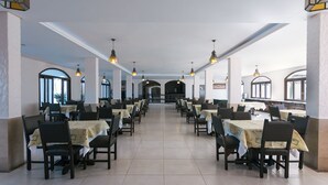 A spacious dining area with multiple tables and chairs, large windows, and hanging pendant lights. - Hotel das Figueiras (Sao Lourenco do Sul)