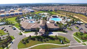 A large resort with multiple swimming pools, a central building, and a parking area.