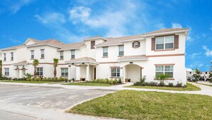 A row of modern two-story townhouses with a uniform architectural style, featuring a flat roof, white exterior walls, and brown window frames. - 1573 Plunker Drive (Davenport)