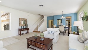 A spacious living room with a staircase, a dining area, and a kitchen. - 221 Las Fuentes Dr (Kissimmee)