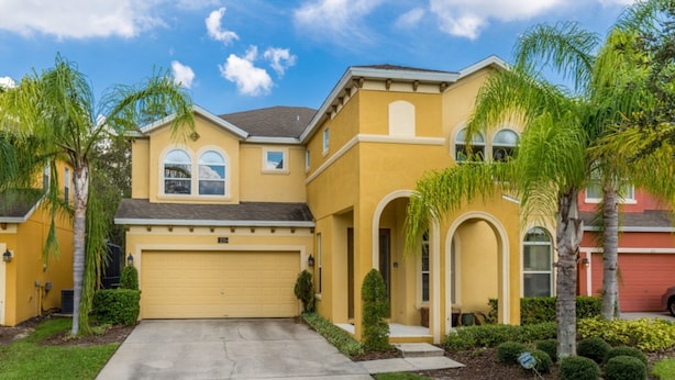 A yellow two-story house with a garage, palm trees, and a well-maintained lawn. - 221 Las Fuentes Dr (Kissimmee)