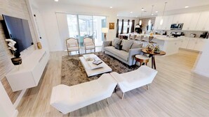 Un salon moderne avec un canapé, une table basse et un grand téléviseur à écran plat.