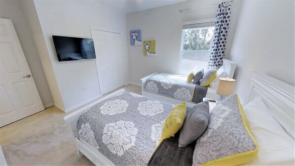 Une chambre avec deux lits, une télévision et des œuvres d’art accrochées au mur.