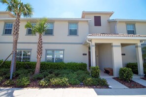 A two-story building with a covered entrance, a palm tree, and a well-maintained garden. - 4815 Crusoe Street (Kissimmee)