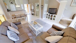 A spacious living area with a sofa set, a coffee table, and a television. - 8523 Crystal Cove Loop (Kissimmee)