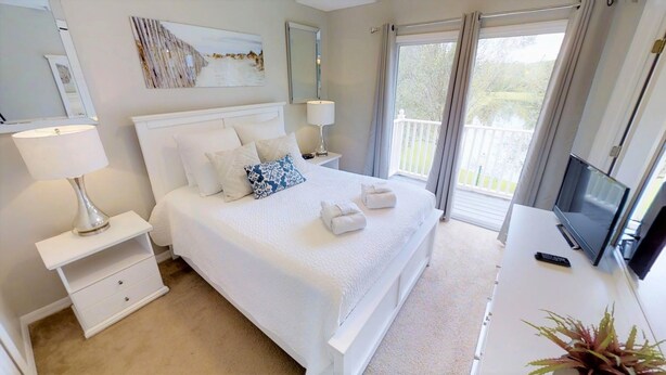 A hotel room with a large bed, a TV, a desk, and a balcony with a view. - 8523 Crystal Cove Loop (Kissimmee)