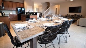 A spacious dining area with a long wooden table set for six, surrounded by black chairs. - 2586 Shanti Drive (Kissimmee)