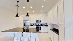 A modern kitchen with a central island, white cabinetry, and stainless steel appliances. - 270 Captiva Dr (Davenport)