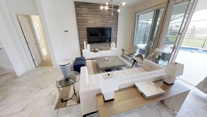 Una sala de estar moderna con un televisor de pantalla plana grande, un conjunto de sofás, una mesa de centro y un comedor.