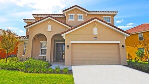 A two-story house with a garage, a front entrance, and a well-maintained lawn. - Solterra Six-bedroom (Davenport)