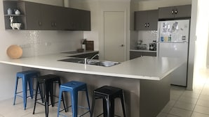 Una cocina moderna con una isla grande, taburetes de bar y un refrigerador.