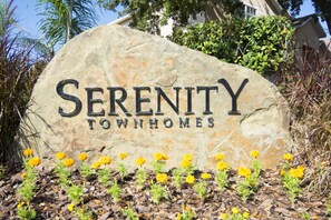 A stone sign with "Serenity Townhomes" written on it, surrounded by yellow flowers and mulch. - The Retreat - 1513 Retreat Circle (Clermont)