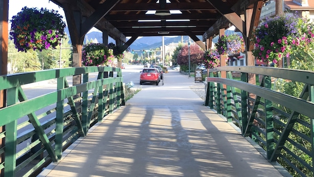 A covered pedestrian bridge with a wooden roof, green railings, and hanging flower baskets. - Cozy Retreat Across from the Clubhouse - 2bd/2ba Condo (Sleeps 6)  (Fraser)