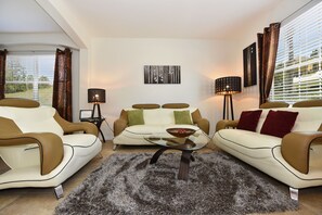 A modern living room with a sofa set, a coffee table, and a floor lamp.