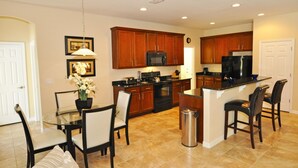 Una cocina moderna con armarios de madera, una isla central con taburetes de bar, microondas, estufa y refrigerador.