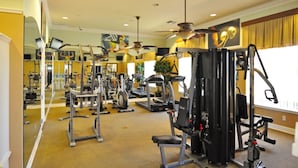 Une salle de sport équipée de divers appareils d’exercice, notamment des tapis de course et des appareils de musculation, disposés dans un espace vaste et bien aménagé.