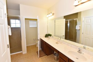 A bathroom with a double sink, a large mirror, and a shower door. - Watersong Resort Five-bedroom (Davenport)