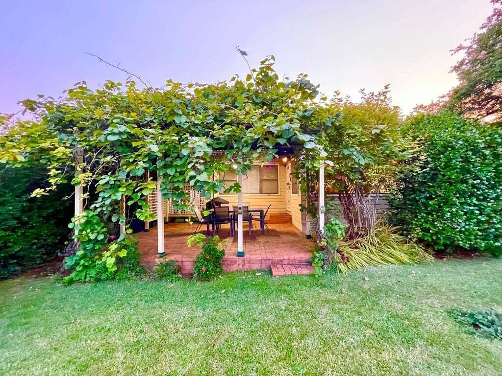 Un'area patio coperta con tavolo e sedie, immersa nel verde.