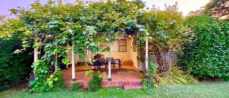 Un'area patio coperta con tavolo e sedie, immersa nel verde.