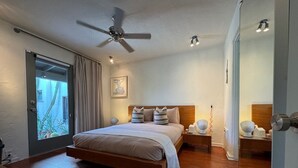 Ein Schlafzimmer mit einem Bett, Nachttischen, einem Deckenventilator und einem Fenster mit Vorhängen.