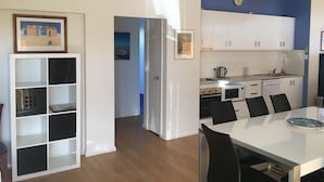 A modern kitchen with white cabinets, a microwave, and a sink. There is a dining table with black chairs and a plate on it. - Golf and Beach Retreat (Collingwood Park)