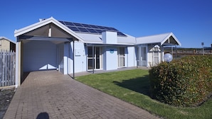 A modern building with a solar panel roof, a covered garage, and a well-maintained lawn. - Golf and Beach Retreat (Collingwood Park)