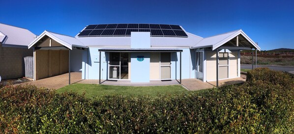 A modern building with a solar panel roof, a covered entrance, and a well-maintained lawn. - Golf and Beach Retreat (Collingwood Park)