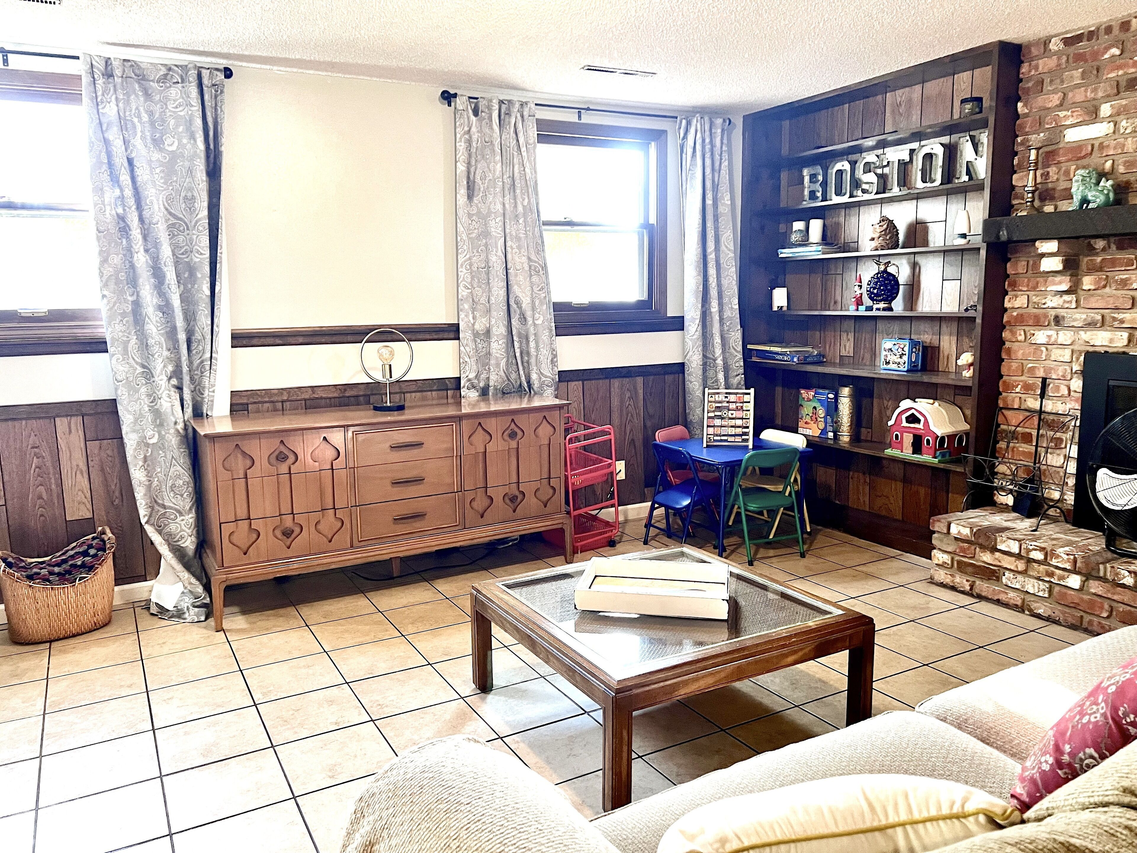A living room with a wooden cabinet, a coffee table, a sofa, a bookshelf, and a fireplace.