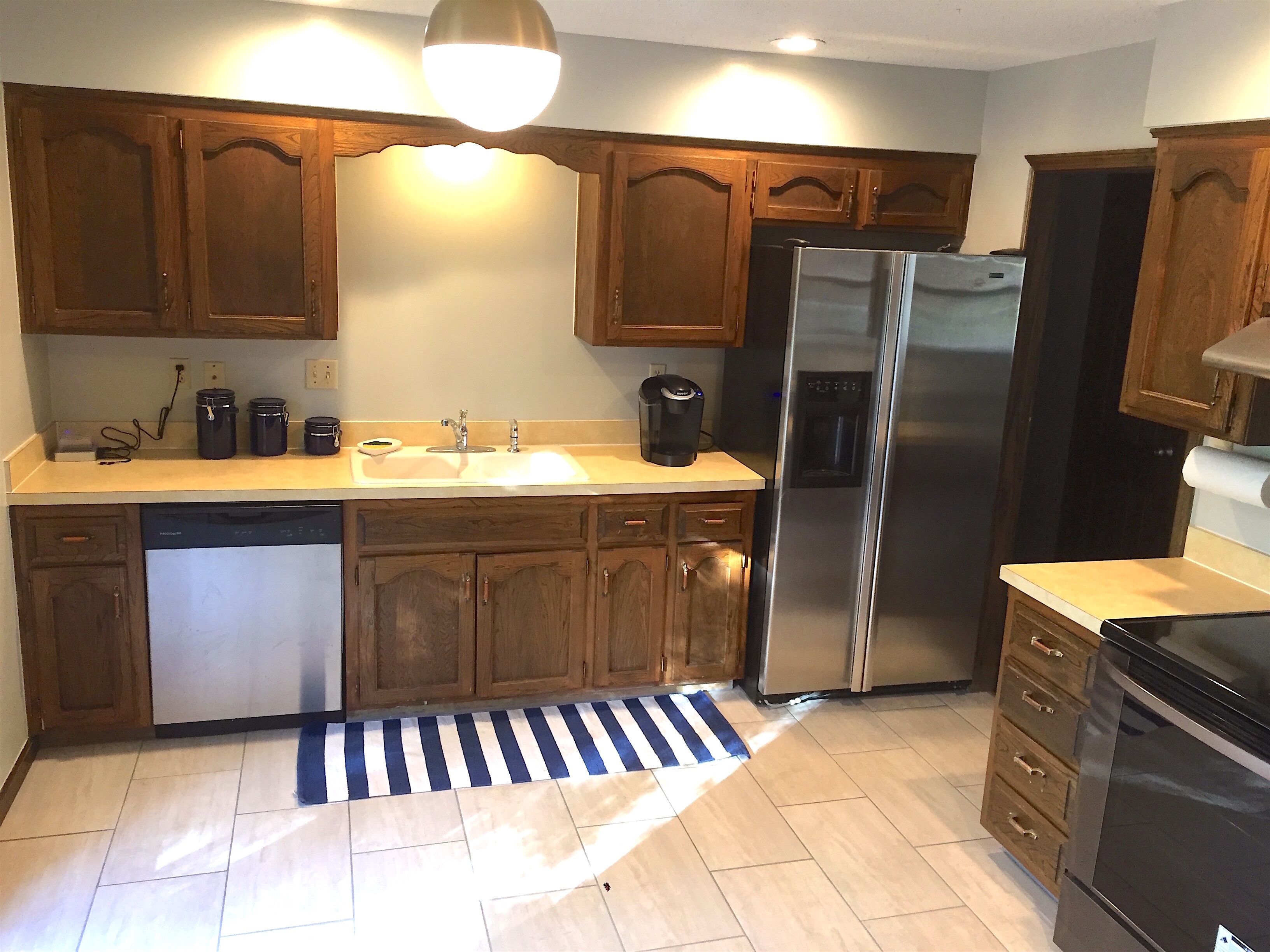 Una cocina con armarios de madera, un refrigerador de acero inoxidable, un lavavajillas y una cafetera.
