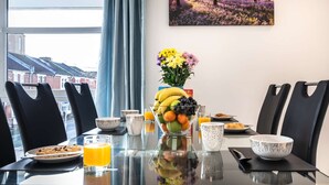 Ein Esstisch mit Obstschale, Blumenvase und Frühstücksgebäck.