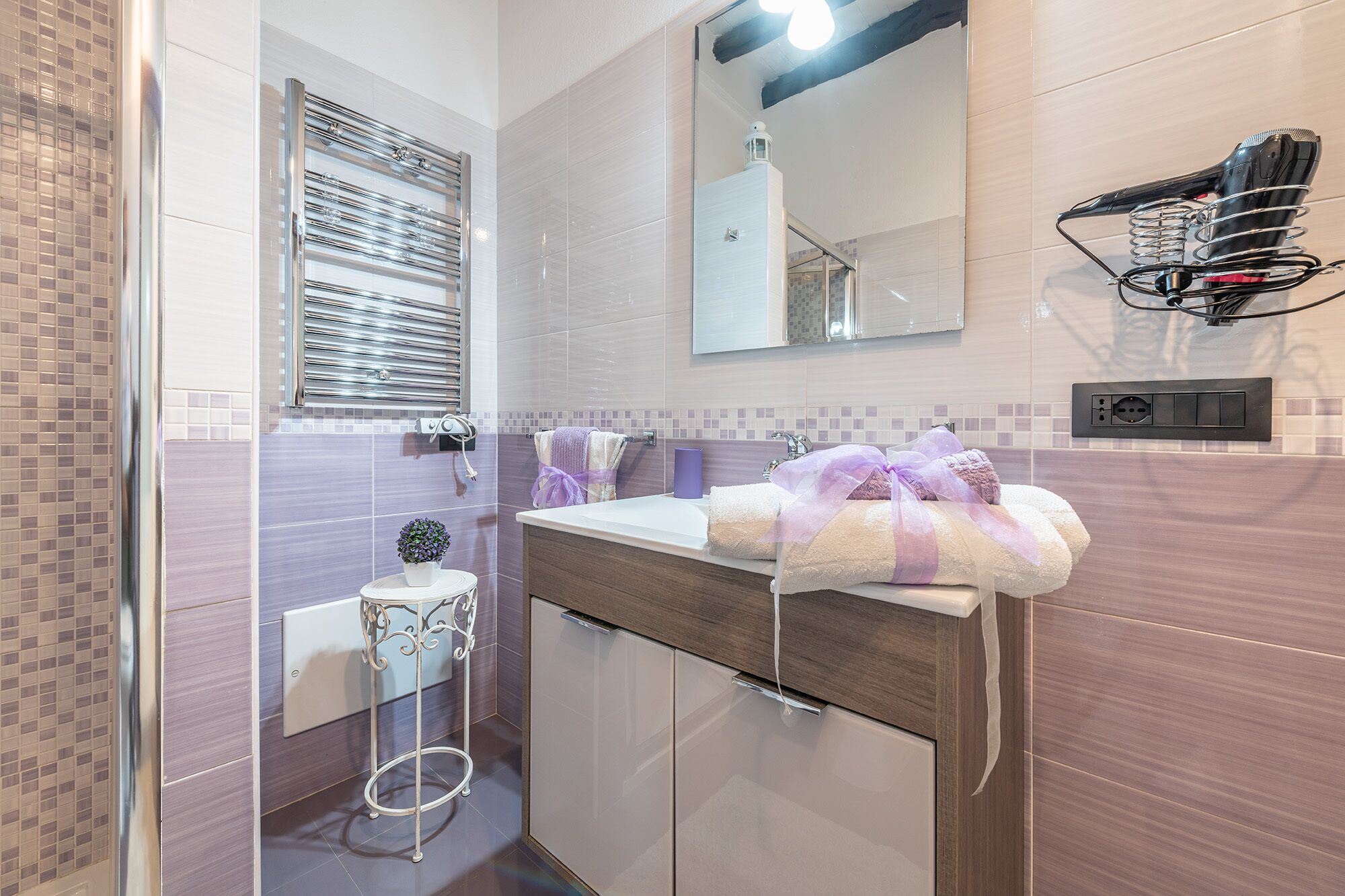 Une salle de bain moderne avec une douche à parois de verre, un meuble-lavabo avec un miroir et un porte-serviettes.