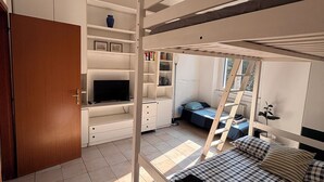 Ein Schlafzimmer mit einem Etagenbett, einem Schreibtisch, einem Fernseher und einem Bücherregal.