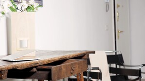 A wooden desk with a laptop, a vase with white flowers, and a black chair with a metal frame. - Luxury appartment in Montenapoleone (120 sqm) with parking in the building (Milano)