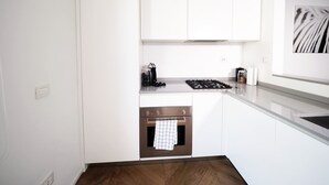 A modern kitchen with white cabinetry, a built-in oven, and a stainless steel range hood. - Luxury appartment in Montenapoleone (120 sqm) with parking in the building (Milano)