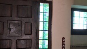 Una puerta de madera con un ventanal, un interruptor de luz en la pared y un ventanal con diseño de cuadrícula.
