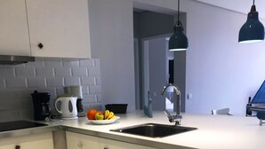 Et moderne køkken med indbygget vaskemaskine, vask og kaffemaskine.
