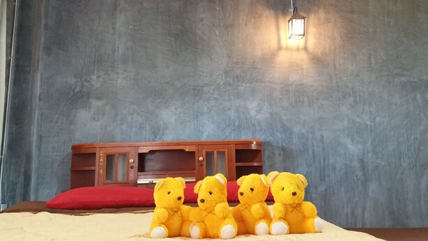 A room with a bed, a red pillow, a wooden cabinet, and four yellow teddy bears. - Baan Saun Homestay by Lamyai Khunmae (Ban Thi)