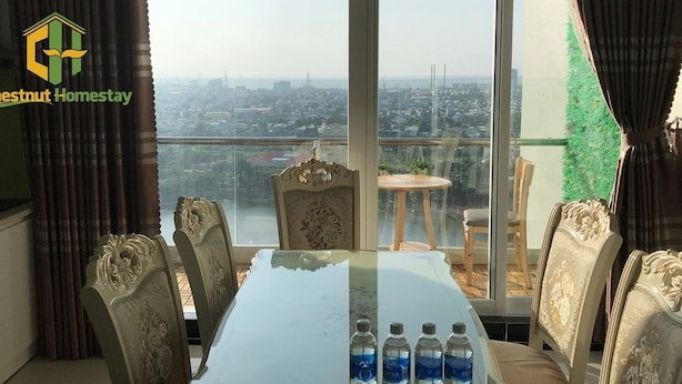Un comedor con mesa de vidrio, sillas ornamentadas y vista a la ciudad.