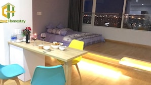 Un dormitorio moderno con cama, una mesa de comedor con sillas y vista a la ciudad desde la ventana.