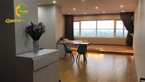 Un apartamento moderno con comedor, un ventanal con cortinas y un florero con flores sobre una encimera.